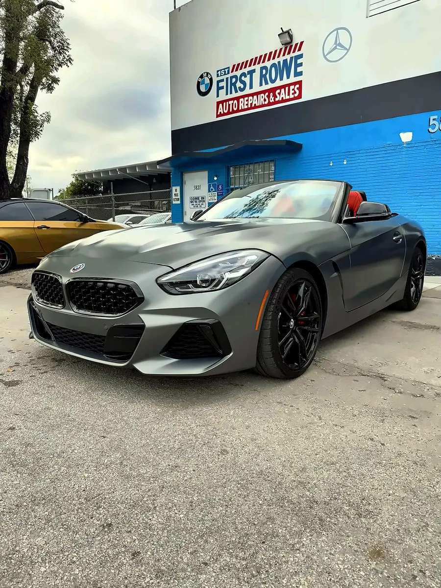 Grey BMW Z4 parked under the First Rowe sign after work in the shop