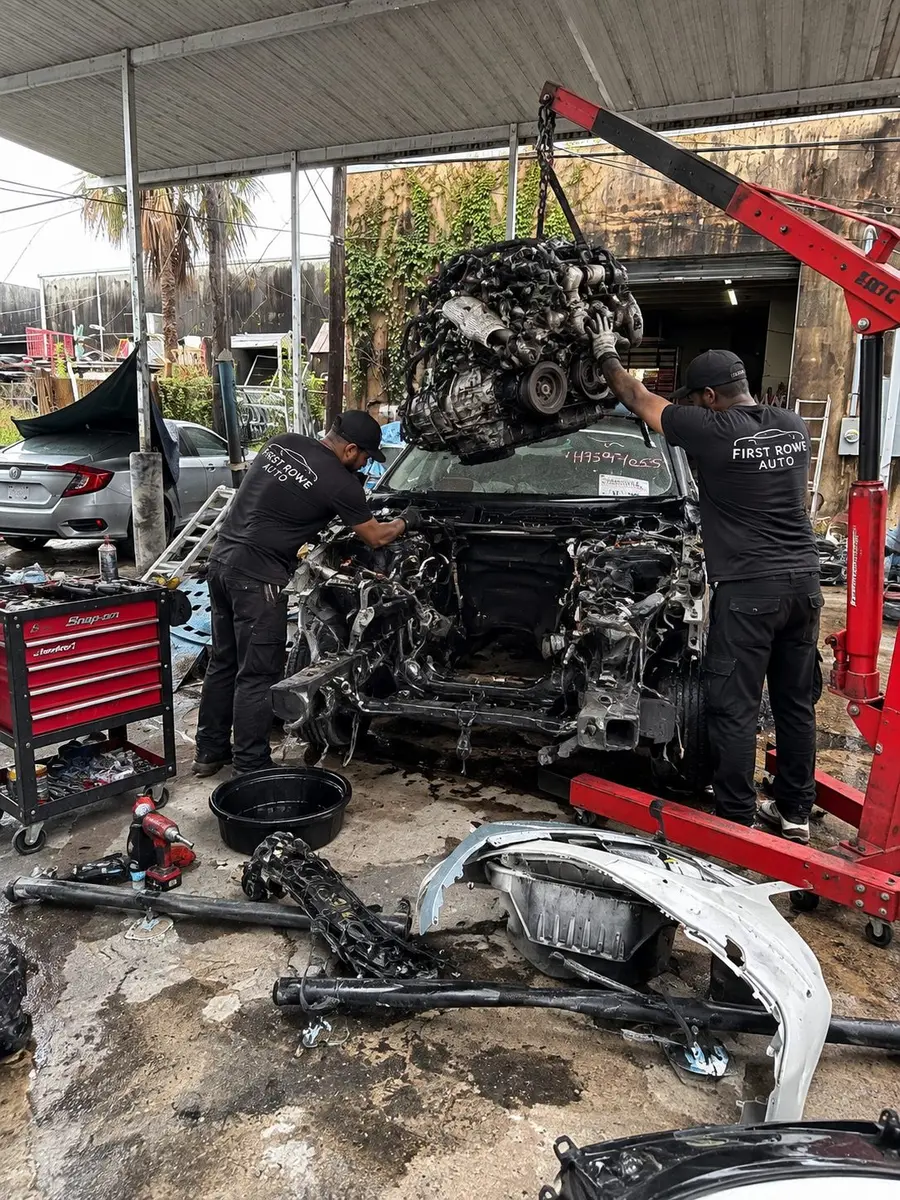 Two First Rowe technicians lifting an engine out with a hoist