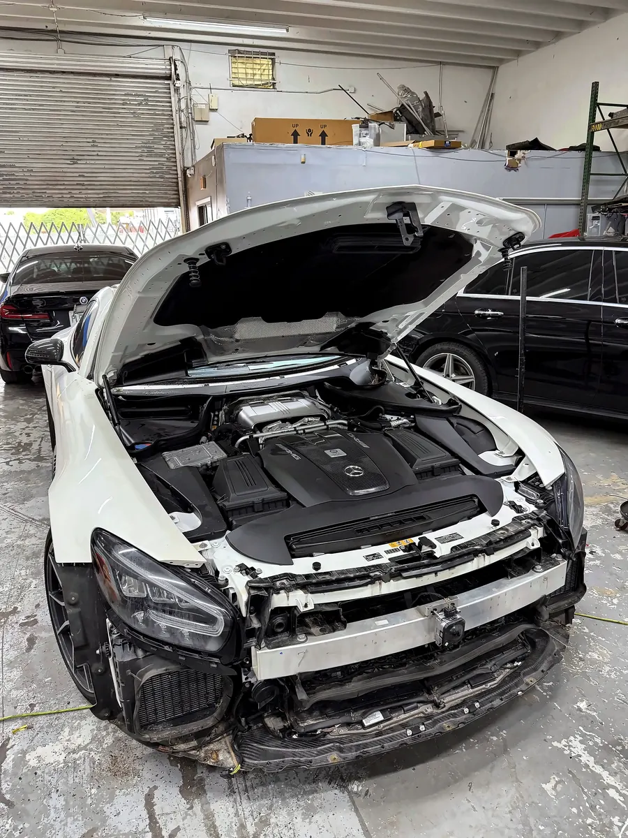 White Mercedes-AMG GT with the hood up and front bumper off in a First Rowe bay
