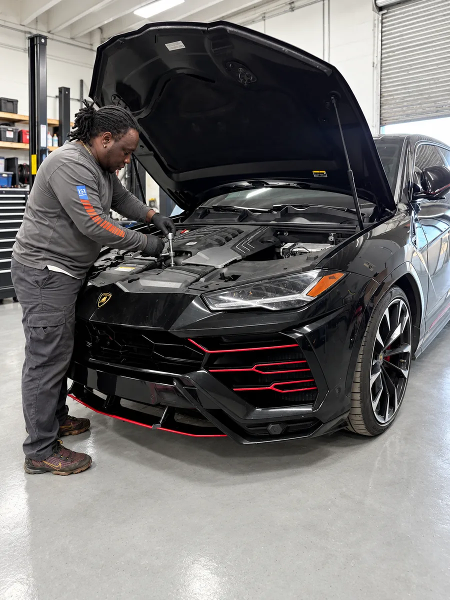 Technician working in the engine bay of a black Lamborghini Urus