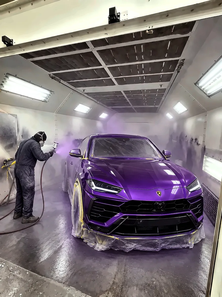 Painter spraying a purple Lamborghini Urus in the paint booth